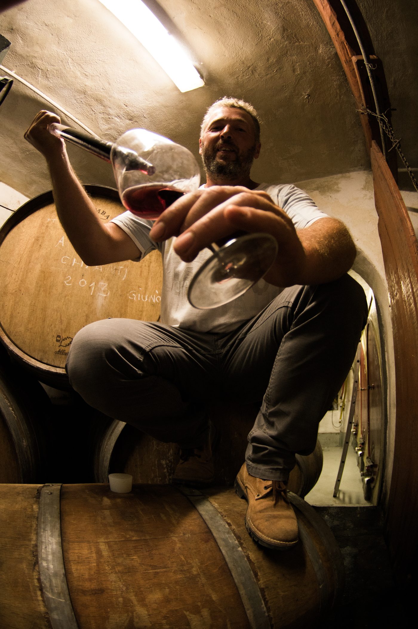 Sauro degusta il vino in cantina, tra le botti